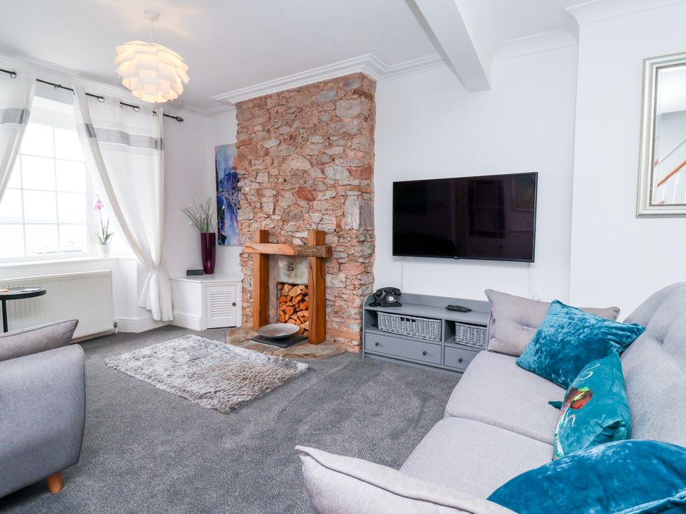 A living room with a stone fireplace and television at 45 North View in Brixham