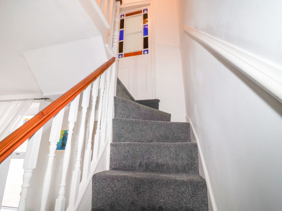 A staircase with carpet and wooden handrail at 45 North View Brixham