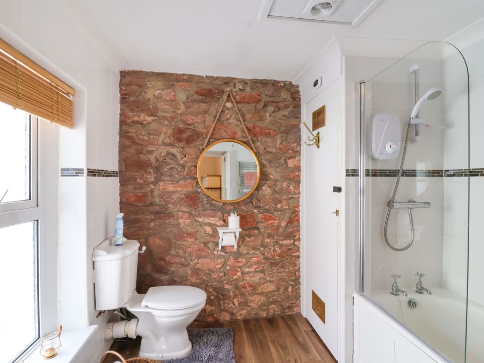 A bathroom with a toilet, shower and mirror at 45 North View Brixham