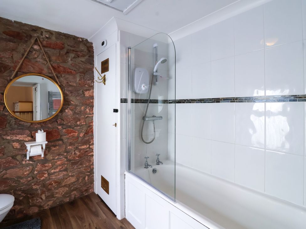 A bathroom with a bathtub, shower, and mirror at 45 North View Brixham