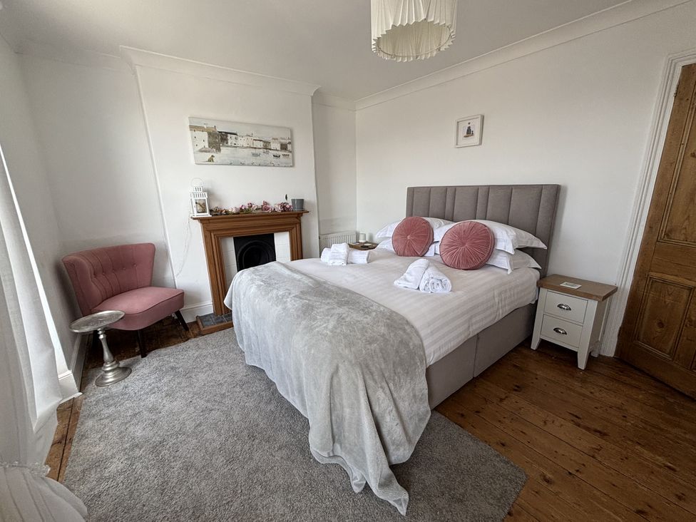 A bedroom with a bed and chair at 45 North View Brixham