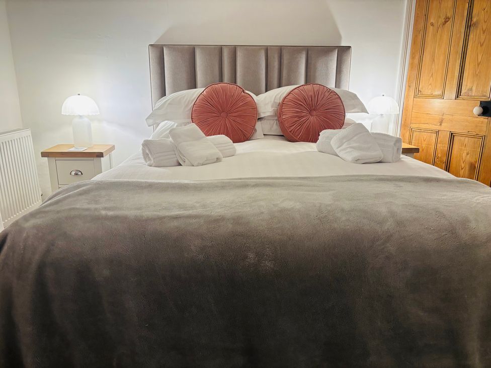 A bedroom with a bed, pillows, towels, and a lamp at Lizzy’s Cottage in Brixham
