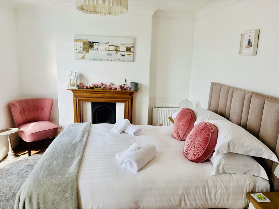 A bedroom with a bed, armchair, and fireplace at Lizzy’s Cottage Brixham