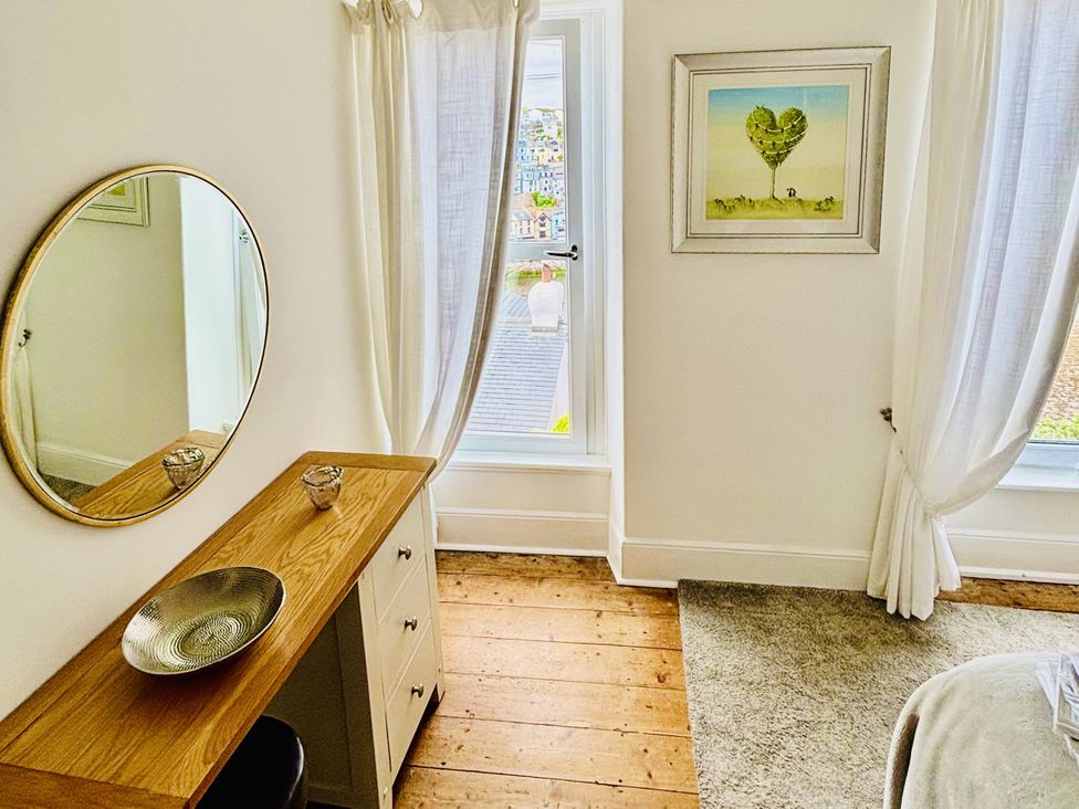 A bedroom with a mirror and a table at Lizzy’s Cottage in Brixham