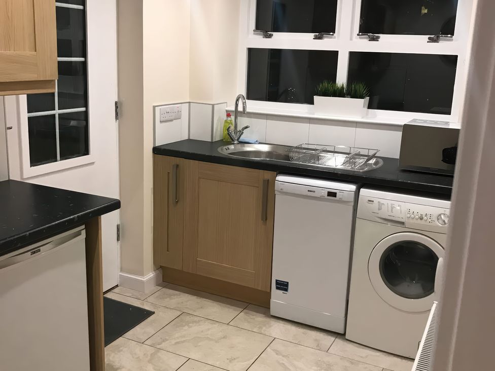 A kitchen with a sink, dishwasher, and washing machine at View Cottage in Inverness