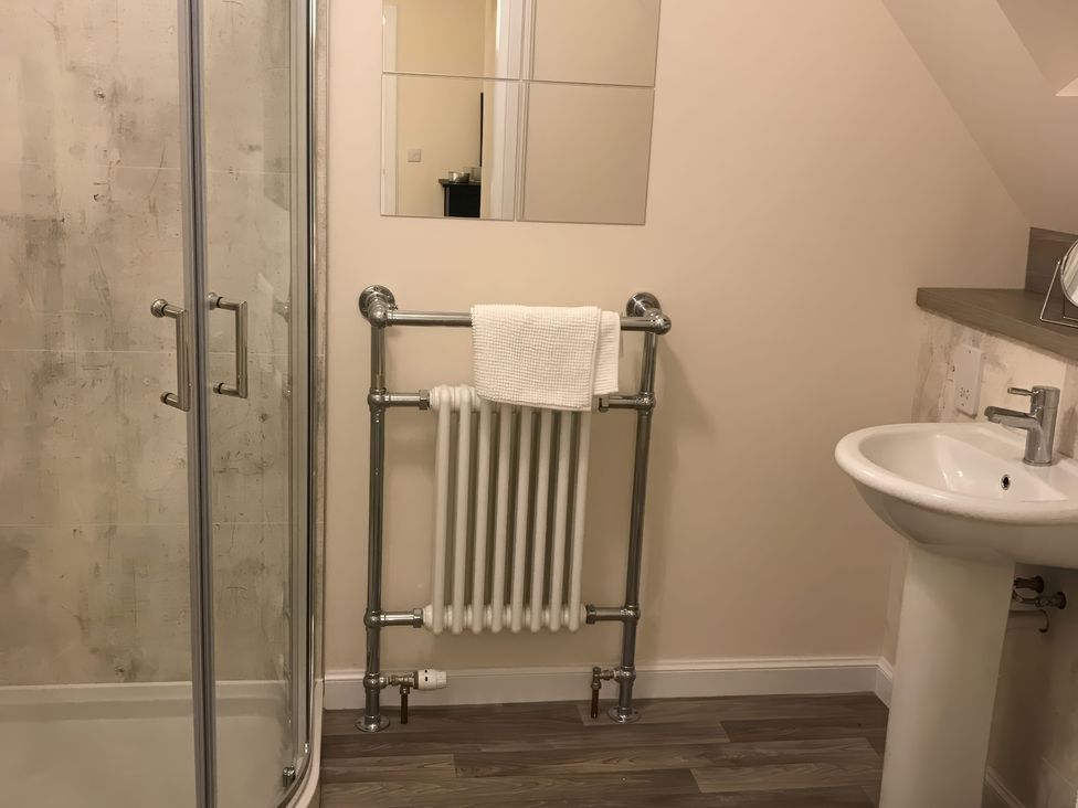 A bathroom with a shower, sink, mirror, and towel rack at View Cottage in Inverness