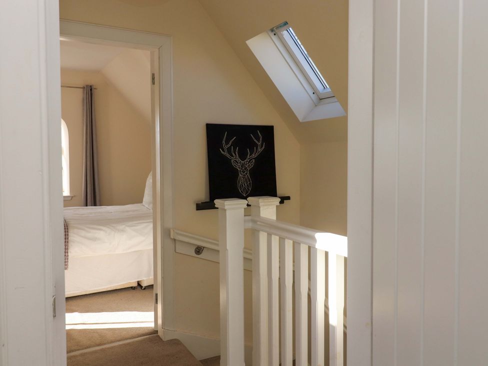 A hallway with a staircase and a decorated wall at View Cottage in Inverness