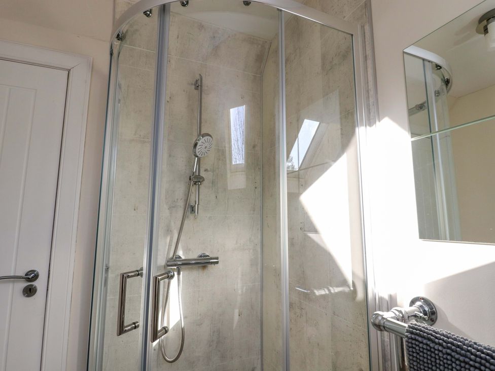 A shower enclosure with a showerhead and a mirror at View Cottage in Inverness