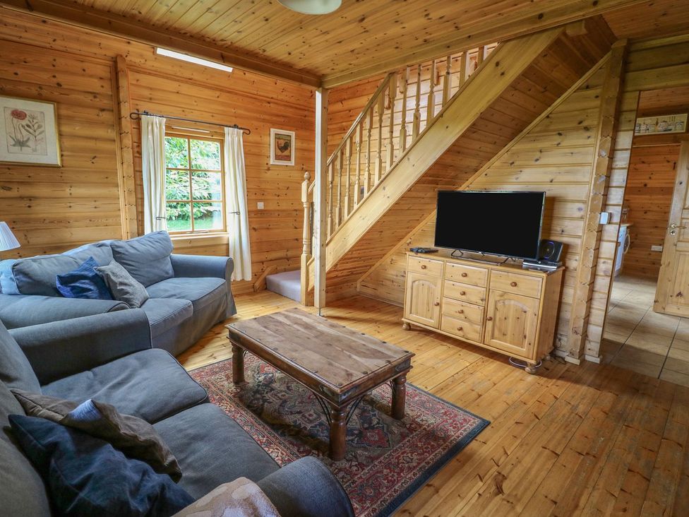 A living room with a sofa, coffee table, and television at Pen Y Clawdd in Beggar's Bush near Presteigne