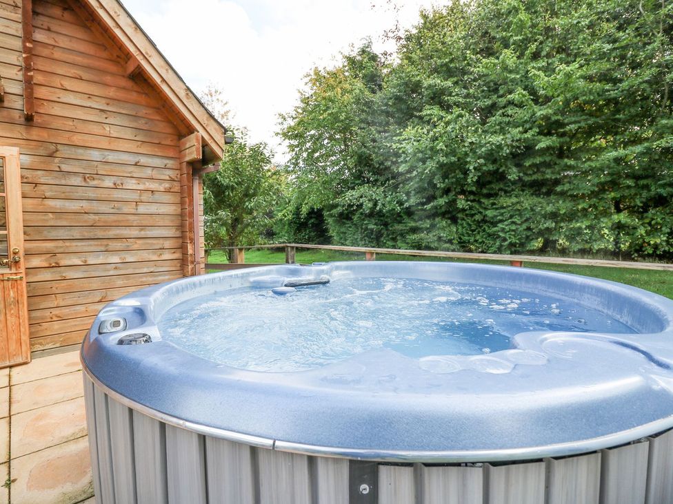 A hot tub beside a wooden cabin at Pen Y Clawdd Beggar's Bush near Presteigne
