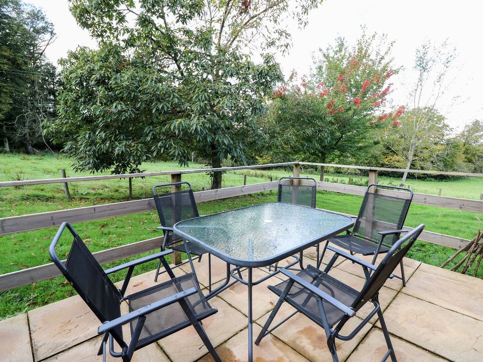 An outdoor seating area with a table and chairs at Pen Y Clawdd near Beggar's Bush