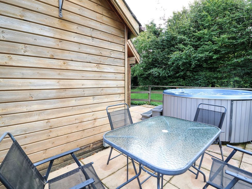 An outdoor area with a table and chairs beside a hot tub at Pen Y Clawdd Beggar's Bush near Presteigne