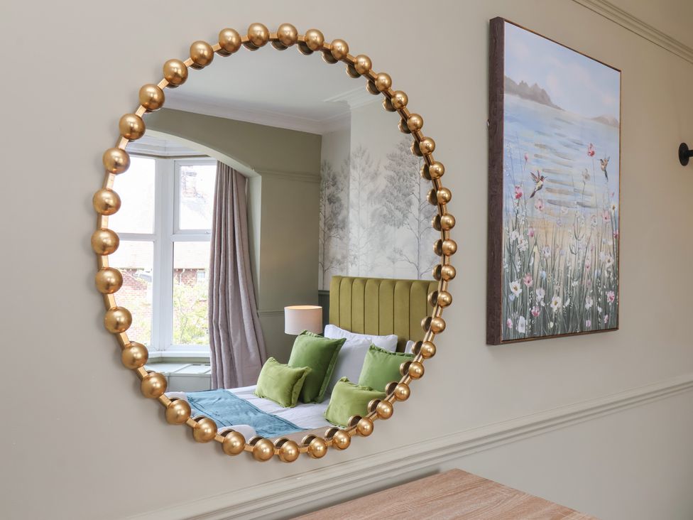 A mirror reflecting a bedroom with a window and picture at Crescent Bay House 