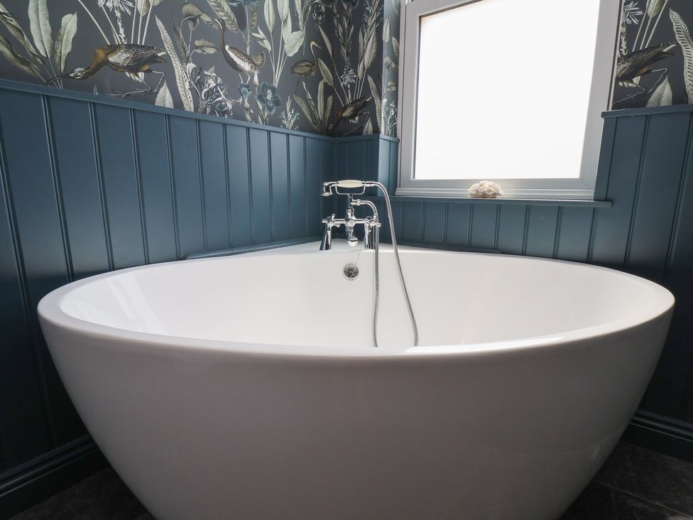 A bathtub with a faucet and window in a bathroom at Crescent Bay House
