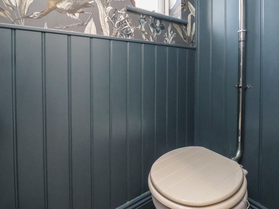 A bathroom with a toilet and decorative wallpaper at Crescent Bay House