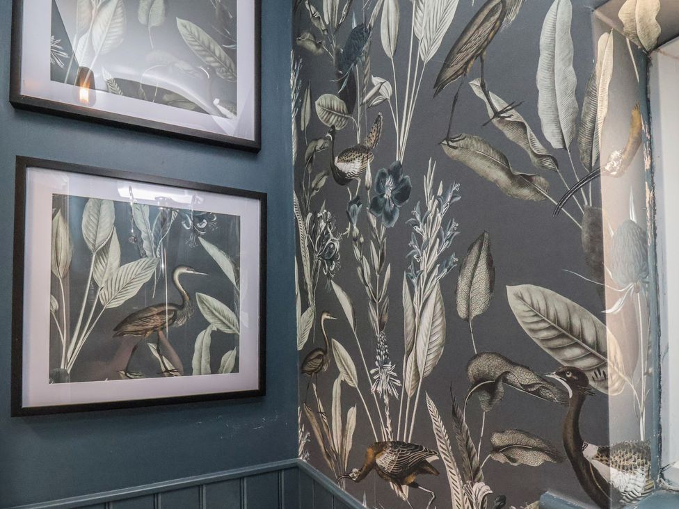 A corridor with framed artworks and patterned wallpaper at Crescent Bay House