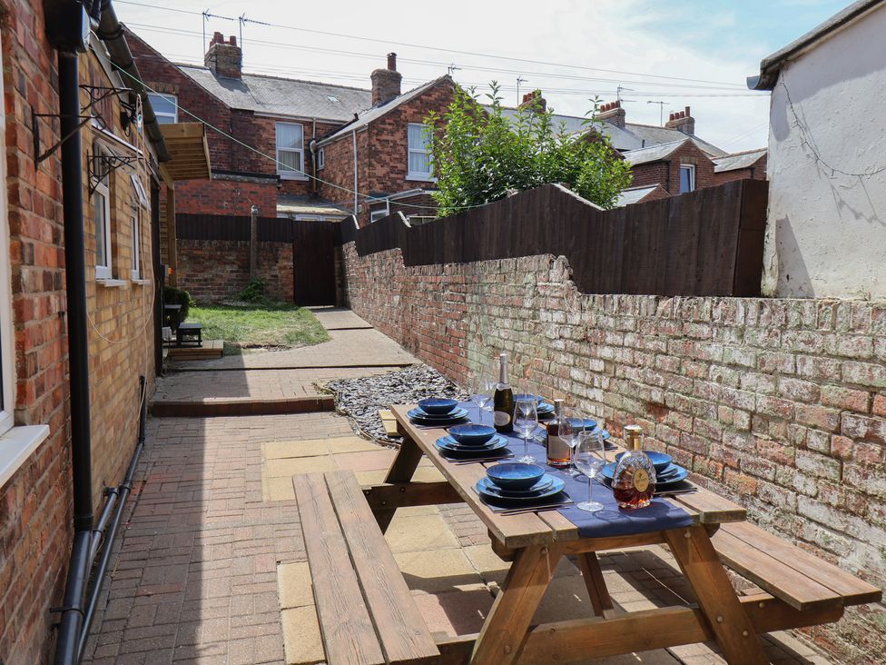 A garden with a dining table set up in Crescent Bay House