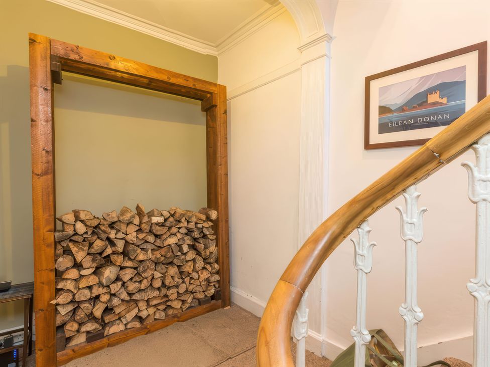 A hallway with a wooden frame for firewood and a staircase at River Cottage in Inverness