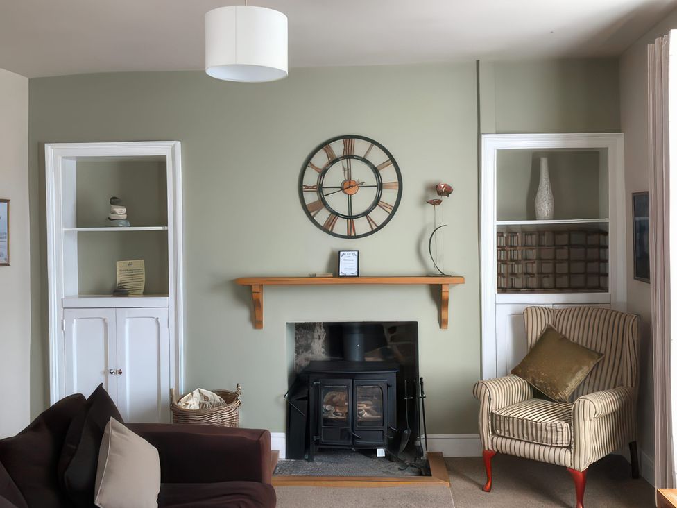 A living room with a fireplace and clock at River Cottage Inverness