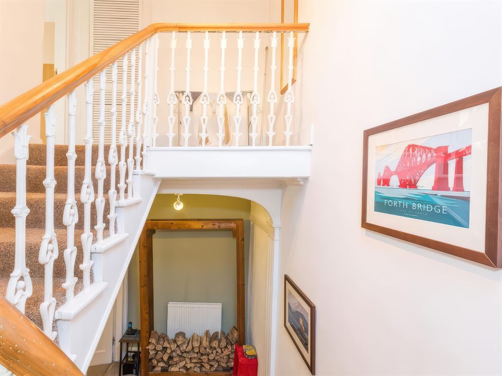 A hallway with stairs and a wood pile at River Cottage Inverness