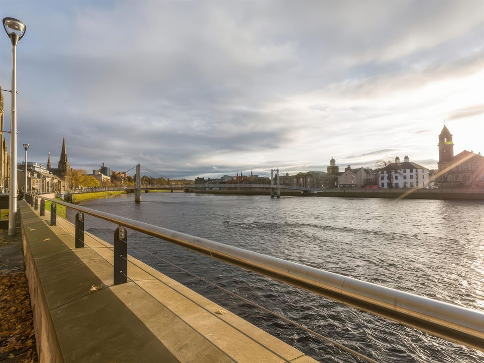A river with buildings and a bridge at River Cottage in Inverness