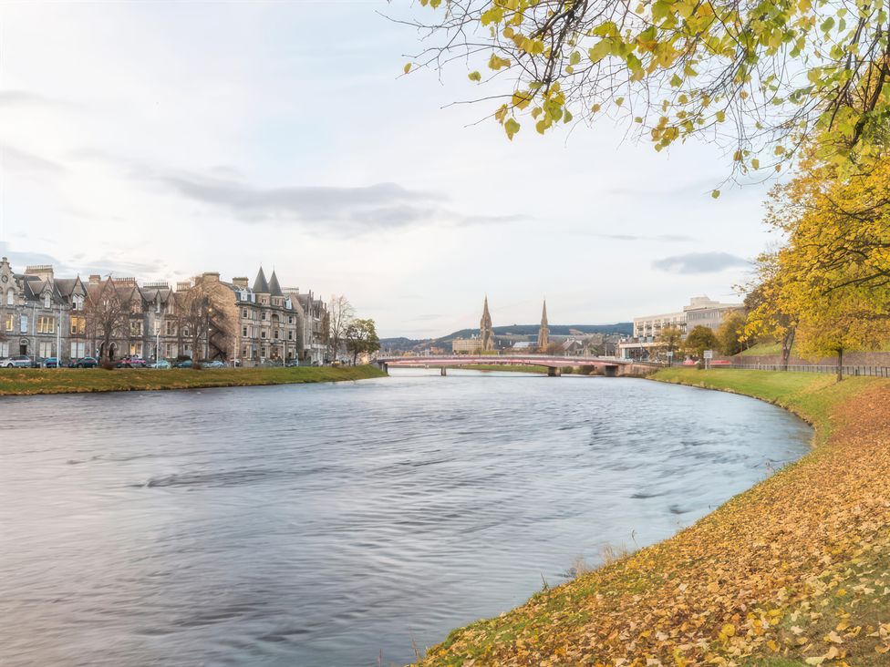 A view of the river with historic buildings and a bridge at River Cottage in Inverness