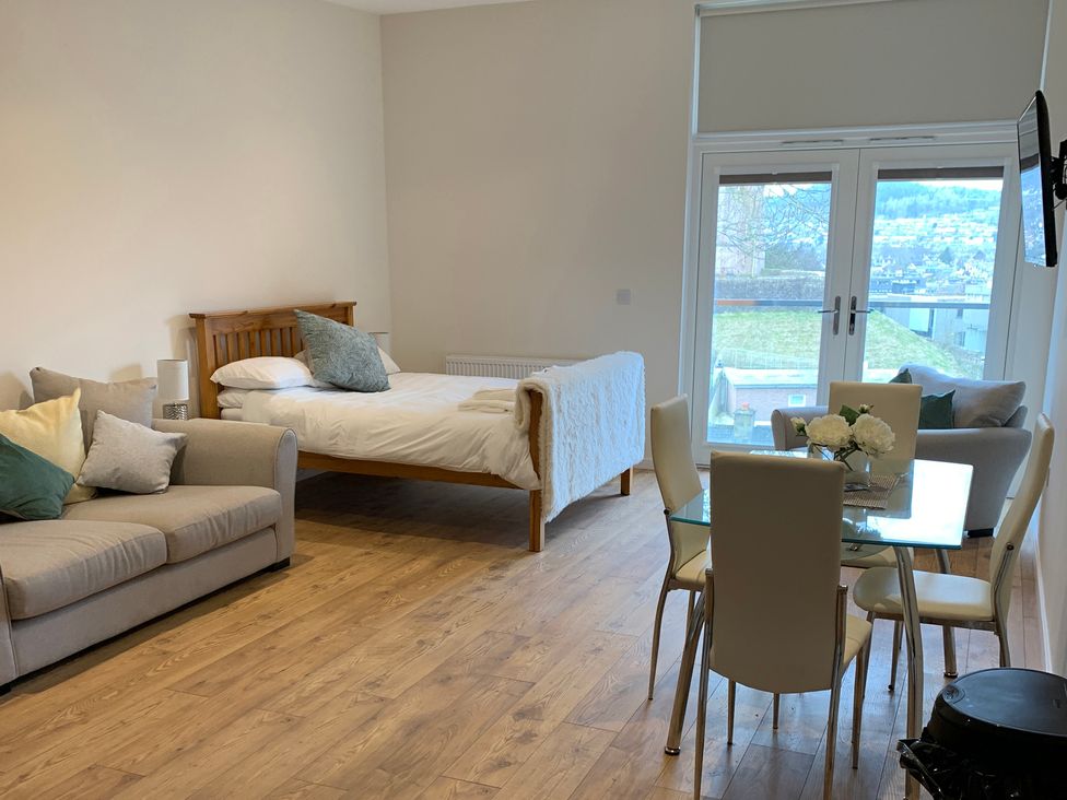A studio apartment with a bed, sofa and dining area at View Apartment in Inverness