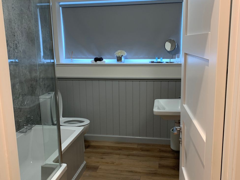 A bathroom with a toilet, bathtub, and sink at View Apartment in Inverness