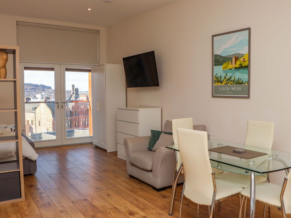 A living room with a sofa, dining table, and large windows at View Apartment in Inverness