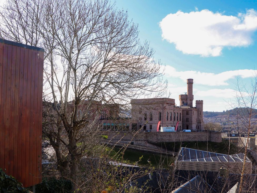 A building with a tower and tree in front at View Apartment Inverness