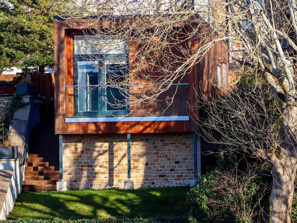A house with stairs and windows surrounded by trees and grass at View Apartment in Inverness