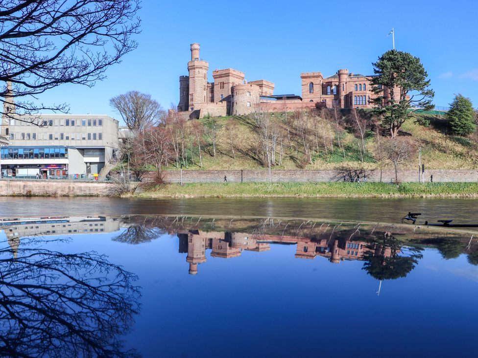 A castle overlooking a river with a reflective surface at View Apartment Inverness