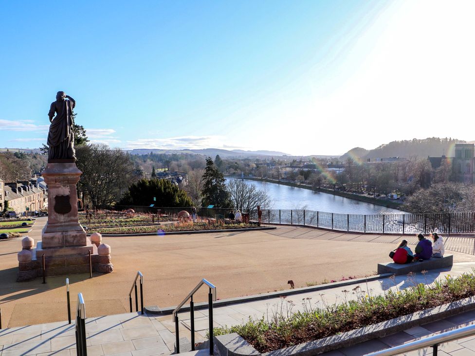 A view of a river with a statue and seating area at View Apartment in Inverness