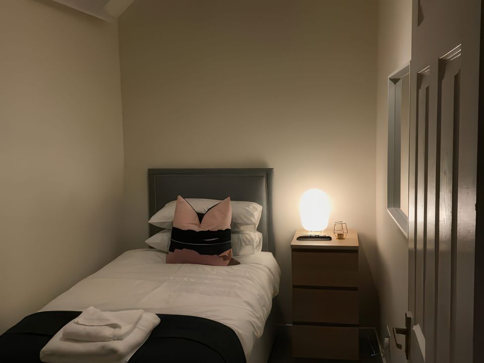 A bedroom with a single bed and nightstand at 2 Lower Kessock Street in Inverness