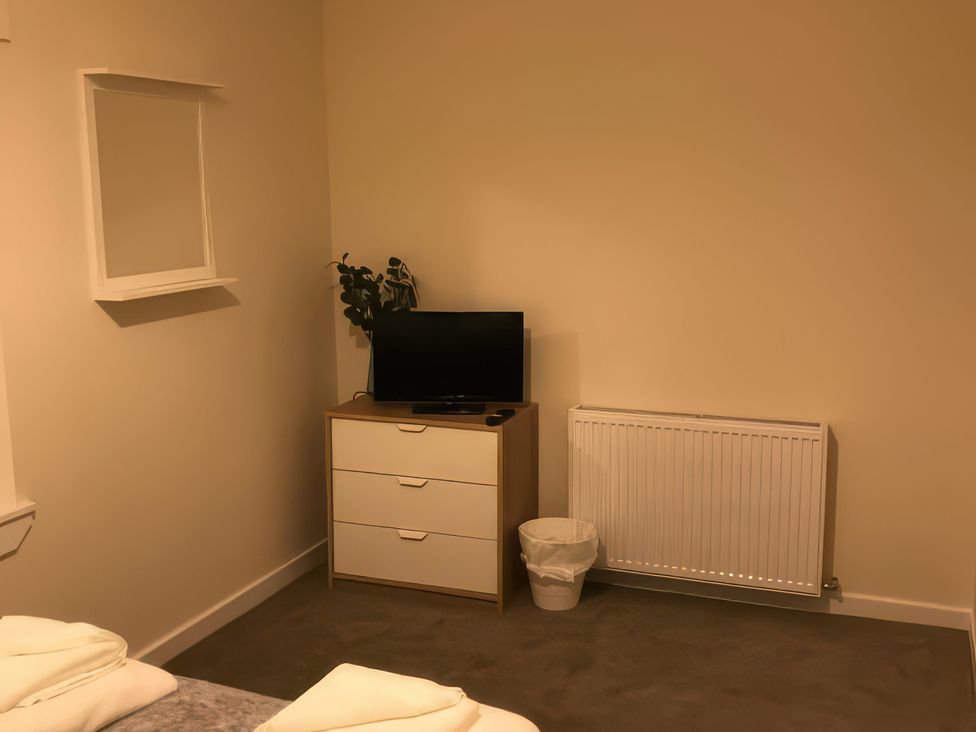 A bedroom with a television and a dresser at 2 Lower Kessock Street in Inverness