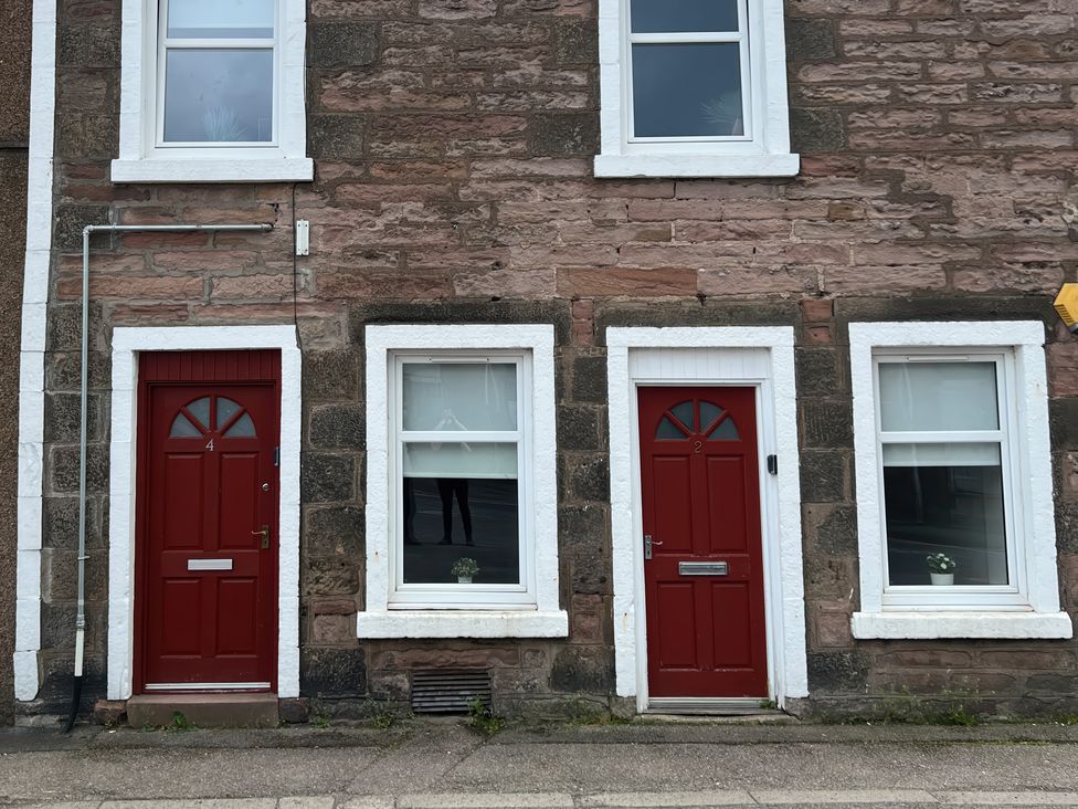 Two red doors and three windows on a stone building at 2 Lower Kessock Street Inverness