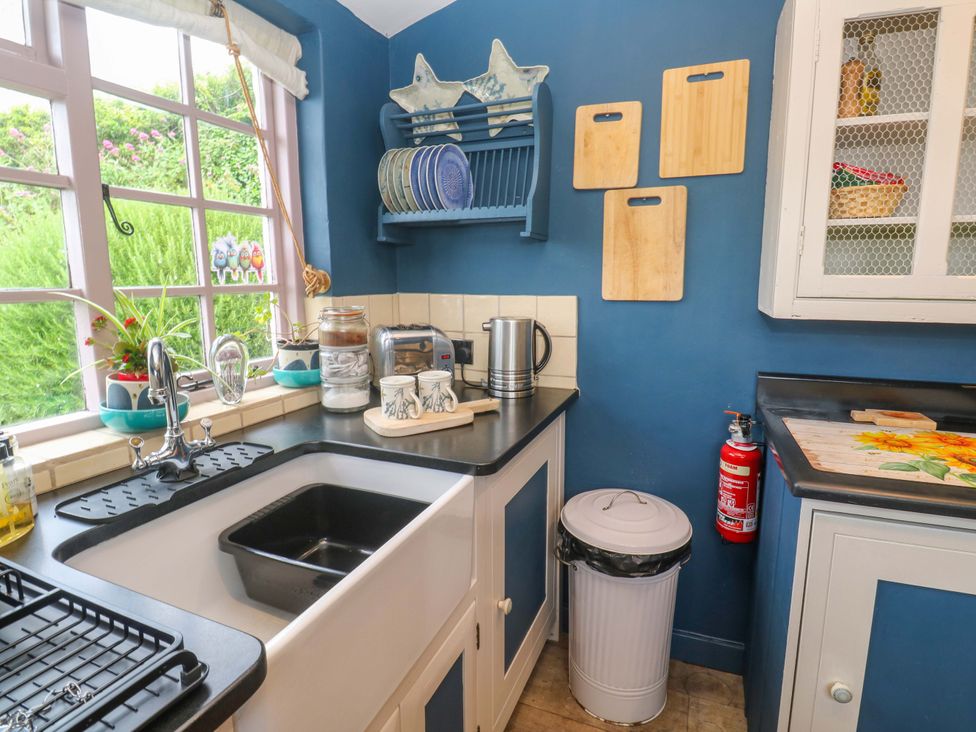 A kitchen with a sink, kettle, and cutting boards at Mermaid Cottage in Coverack near St Keverne