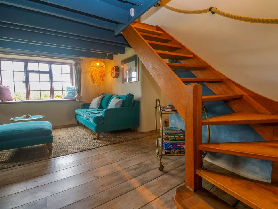 A living room with a sofa and staircase at Mermaid Cottage in Coverack near St Keverne