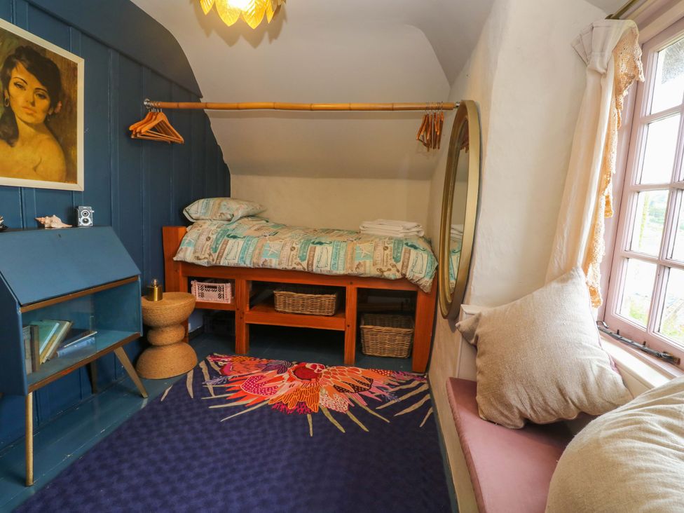 A bedroom with a bed, mirror, and rug at Mermaid Cottage in Coverack near St Keverne