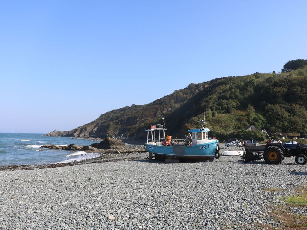 A boat and tractor on a beach near water at Mermaid Cottage in Coverack near St Keverne