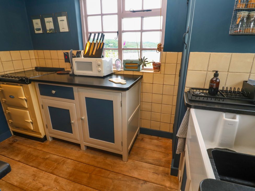 A kitchen with an oven, microwave, and sink at Mermaid Cottage in Coverack near St Keverne