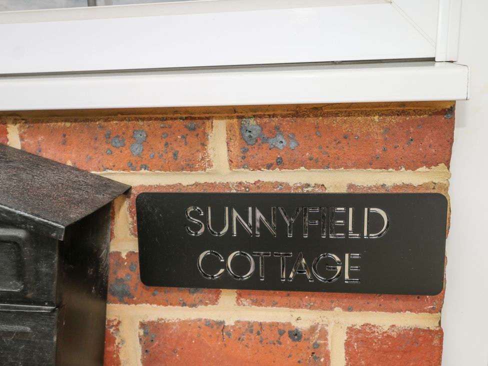 A nameplate on a brick wall with Sunnyfield Cottage at Sunnyfield Cottage 