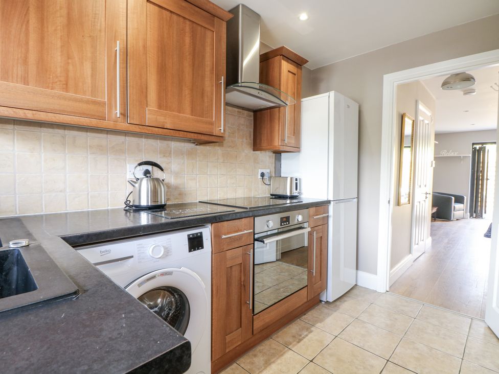 A kitchen with wooden cabinets and appliances at Sunnyfield Cottage