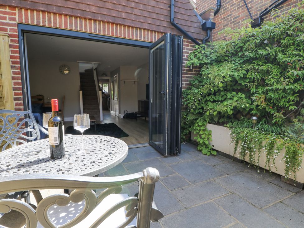 A patio with a table and wine bottle at Sunnyfield Cottage