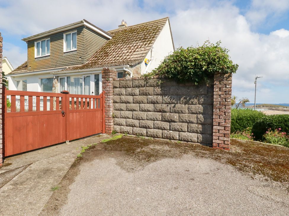 A house with a red gate and stone wall at 22 Pentire Avenue in Newquay