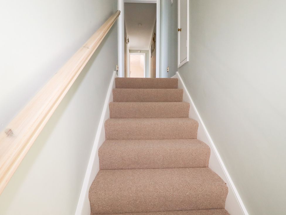 A staircase with carpet and a handrail at 22 Pentire Avenue in Newquay