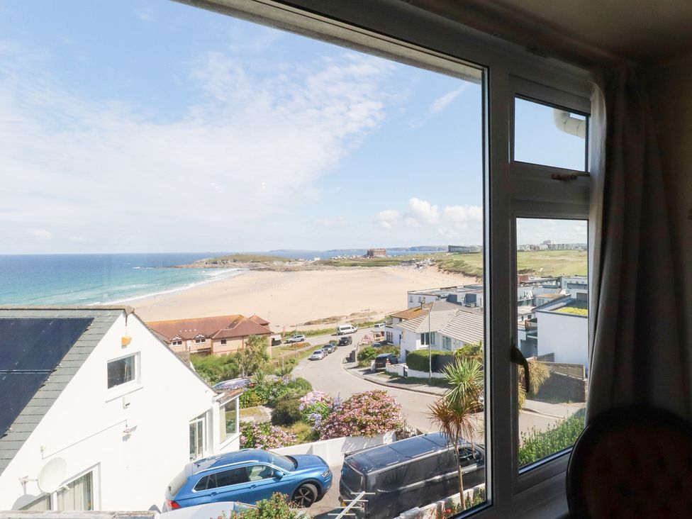 A view of the beach and ocean through a window at 22 Pentire Avenue in Newquay