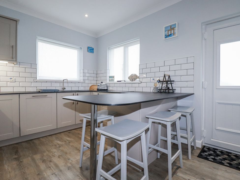 A kitchen with cabinets and bar stools at Pipers in Newquay