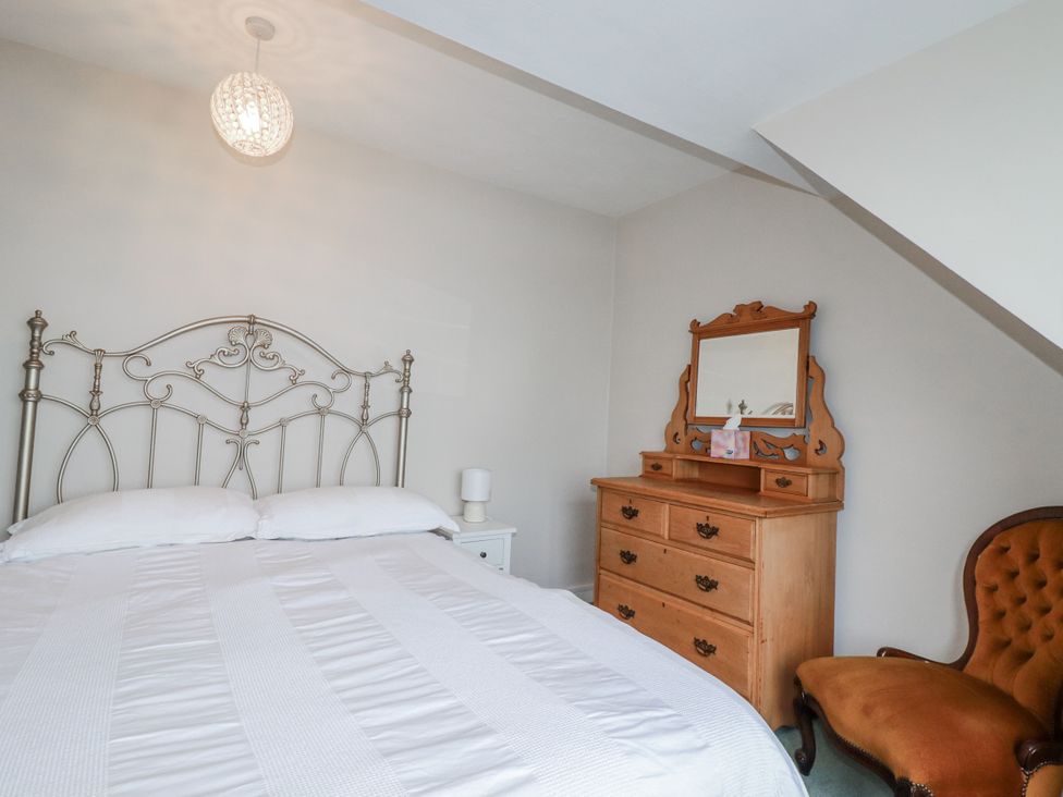 A bedroom with a metal bed and wooden furniture at Pipers in Newquay