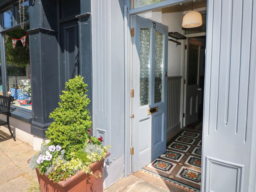 An open door with patterned tiles inside and a planter with greenery and flowers outside